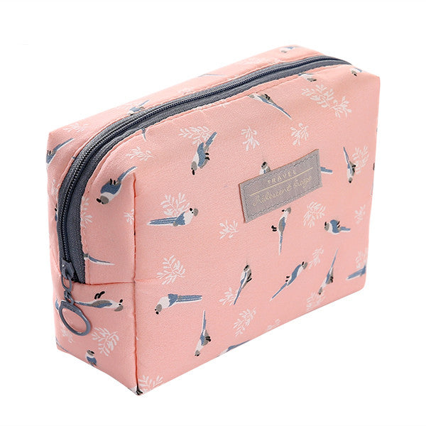 The Daily Drop portable travel cosmetic bag in pink with bird patterns, perfect for cosmetic storage on the go.
